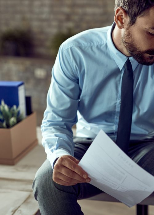Young frustrated businessman holding his head in pain after being fired at work.